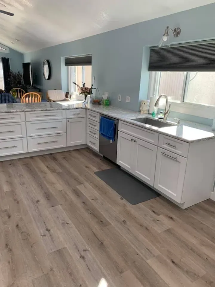 Open kitchen with white cabinets and light plank flooring