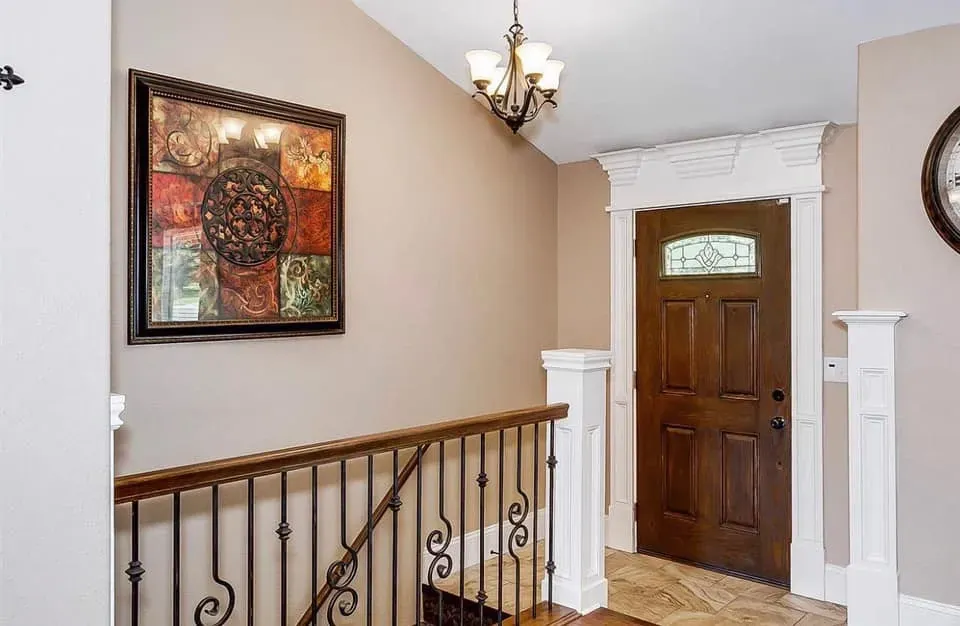 Entry hall with a hardwood floor, wood door and iron railing