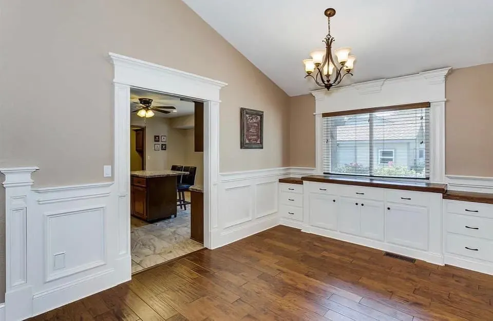 Kitchen nook with white wainscot, cabinets and hardwood flooring