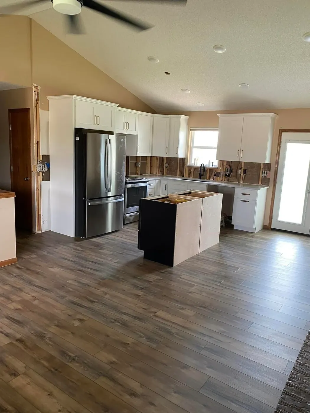 Kitchen with white cabinets, an island and dark plank flooring