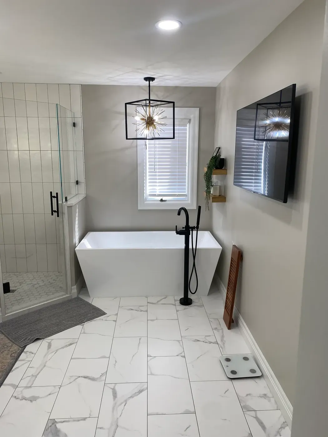 Bathroom with a freestanding tub and white marble look floor tile