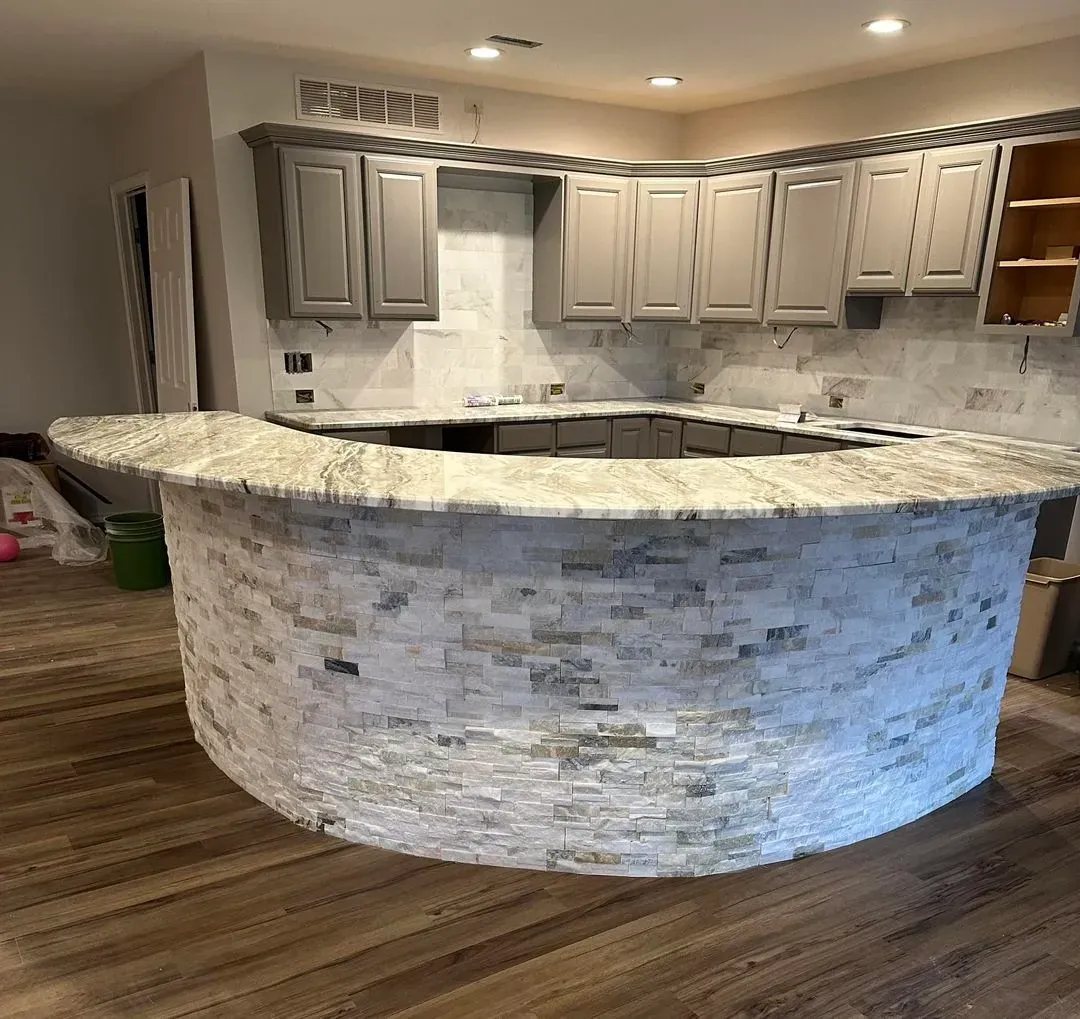 Curved kitchen bar clad in stone tile with a granite top