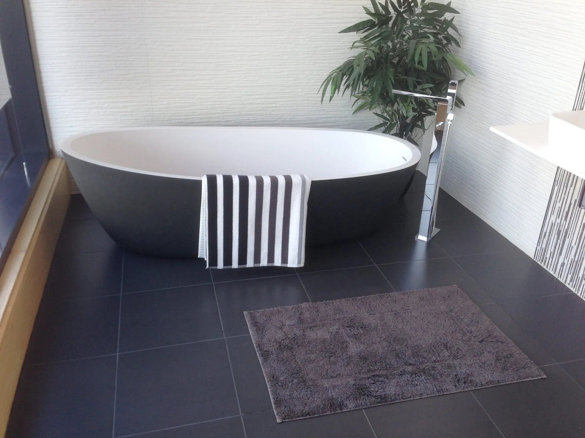 Freestanding tub on a dark tile bathroom floor