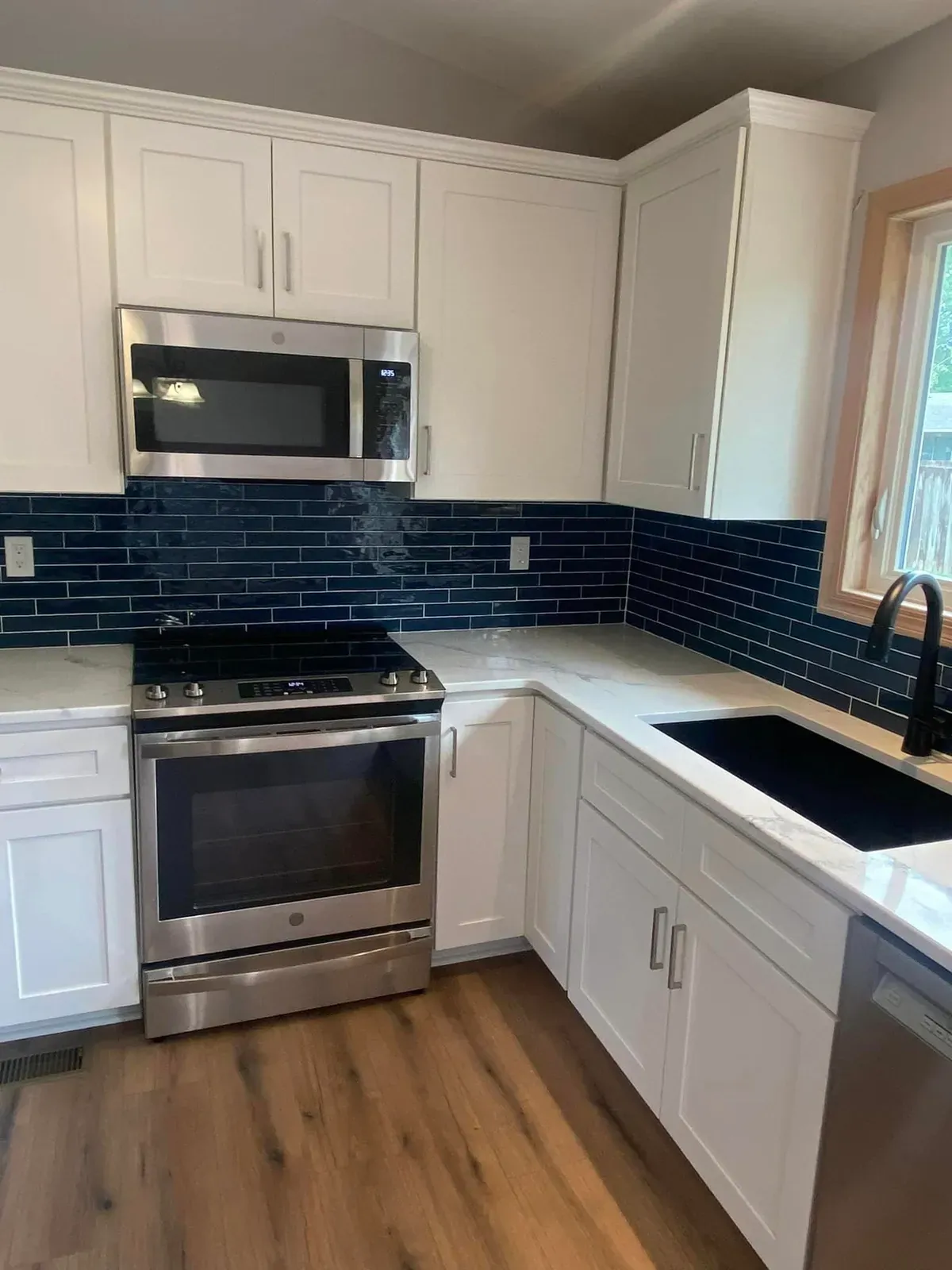 Kitchen with white cabinets, navy tile backsplash and a stainless range